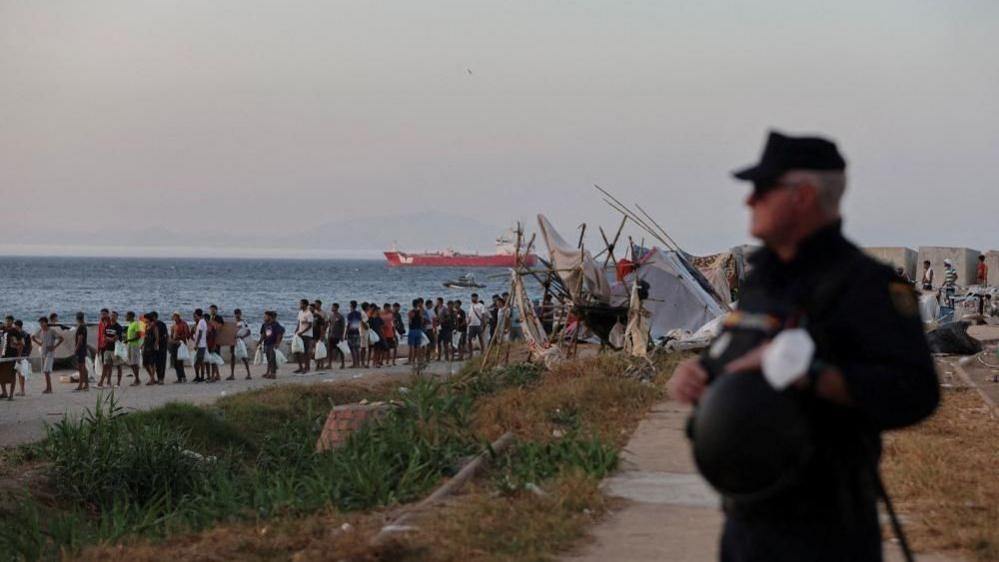 Migrants queuing for aid at Trampolin beach, Ceuta