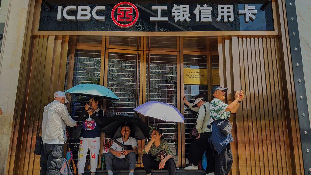 People sit outside a bank counter in Chongqing