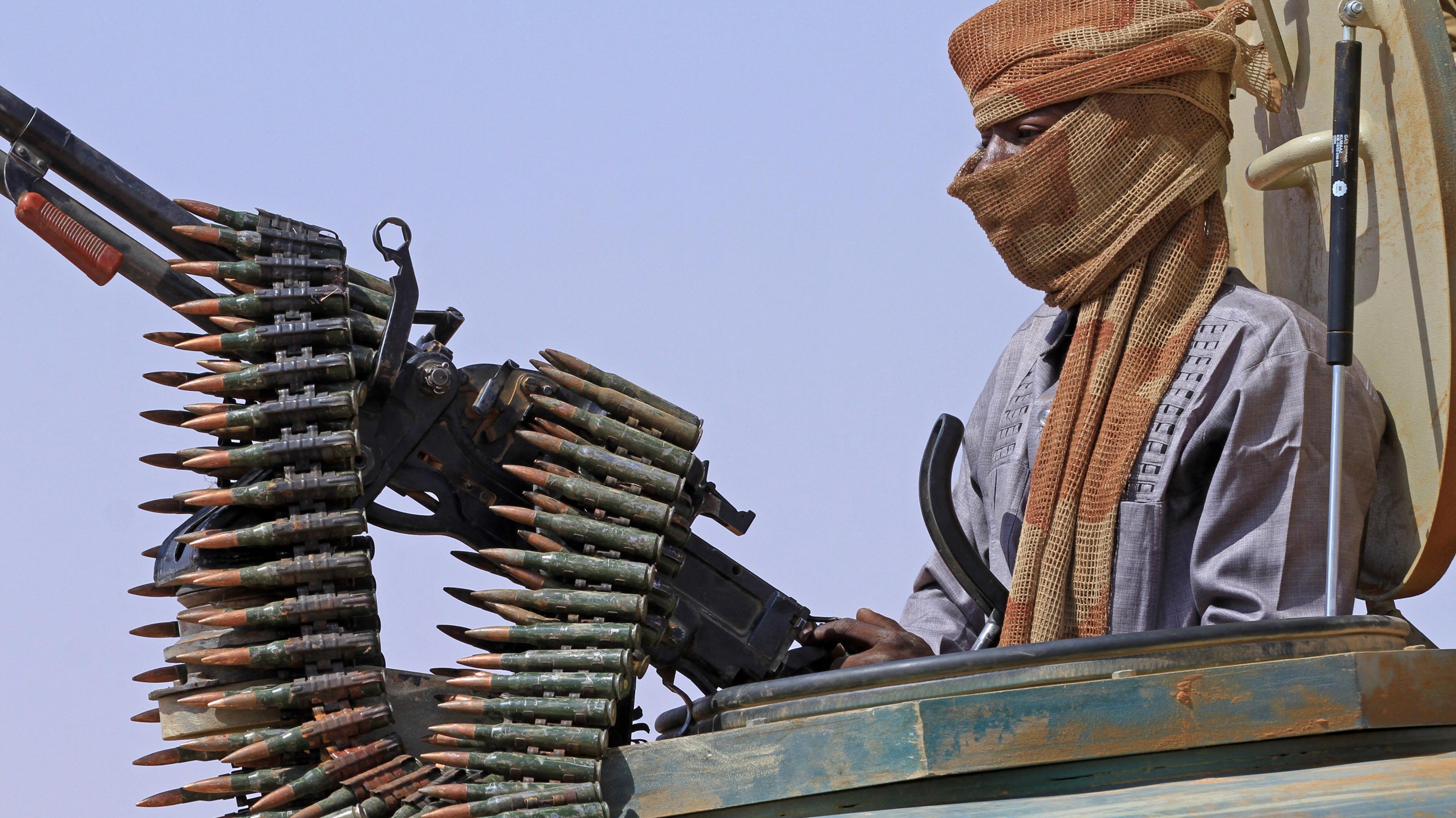 Image of a defector from the RSF standing in an armed vehicle with a mounted gun and a chain of bullets
