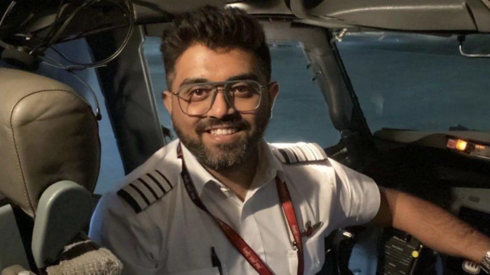 Indian pilot Smit Machchhar smiling into a camera in the cockpit of a plane