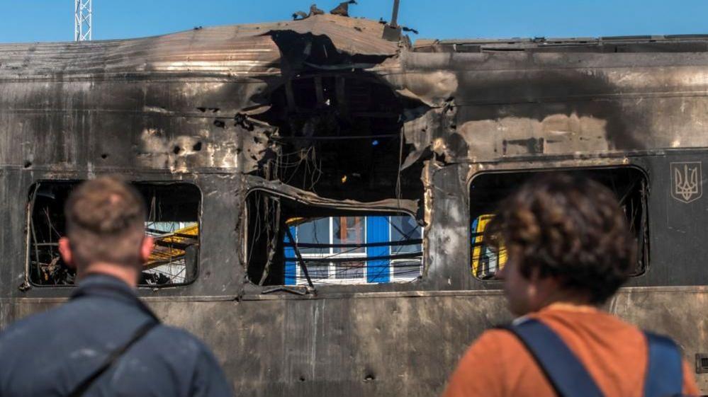 Passengers evacuate a train on the tracks during a drone strike