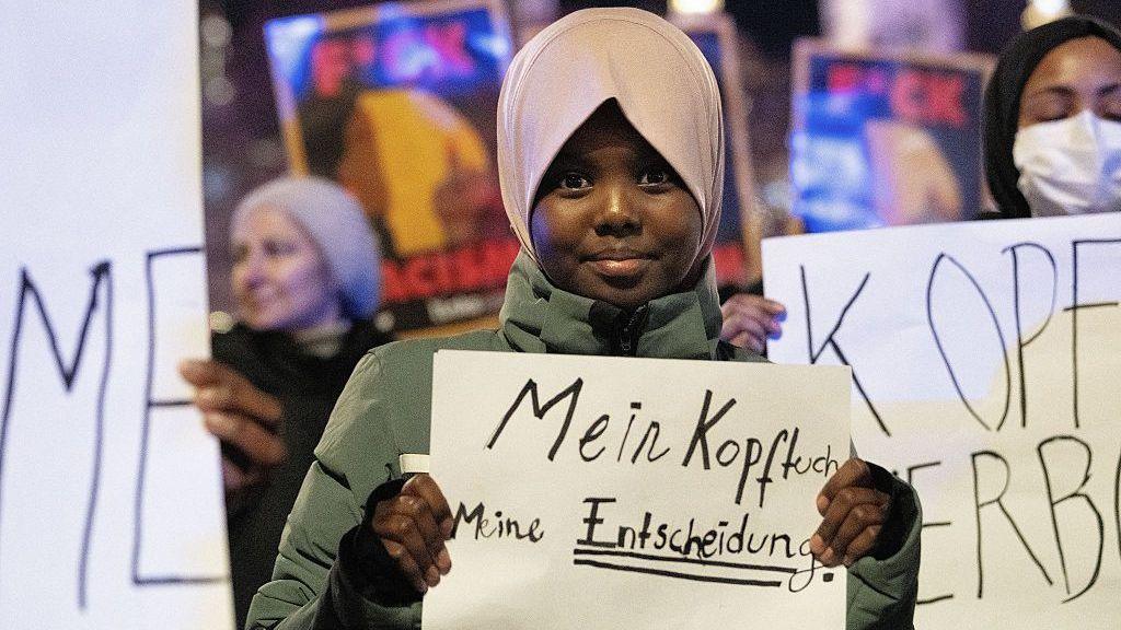 An 11‑year‑old girl protests against the headscarf ban in Vienna, holding a banner that reads "my headscarf, my decision"