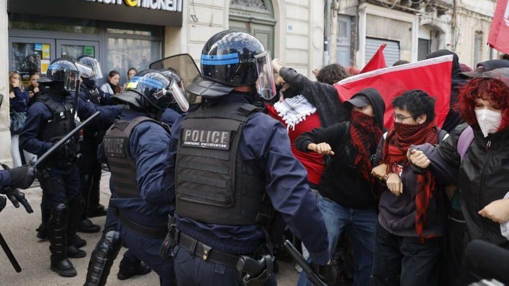 Masked students face riot police