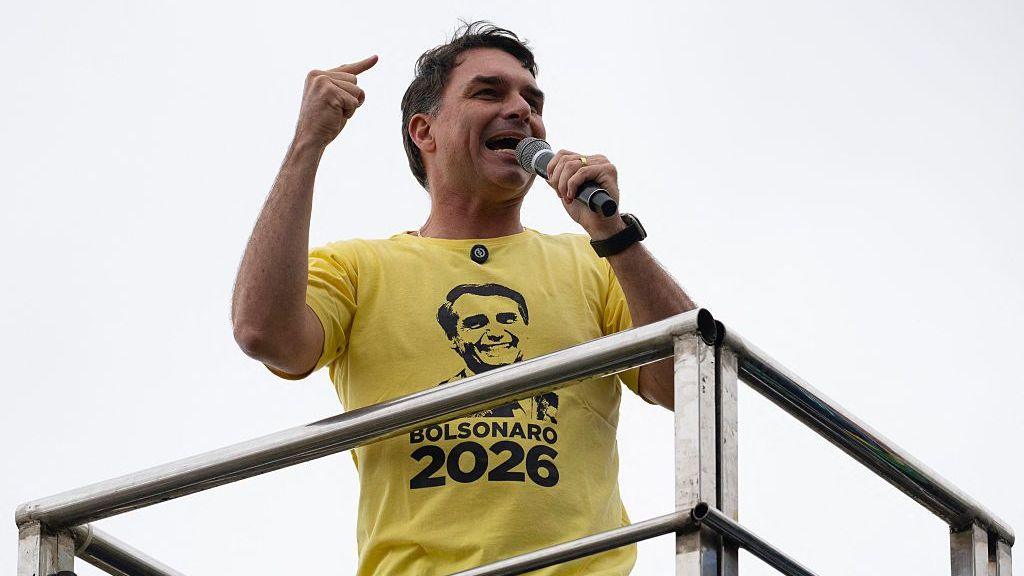 Flávio Bolsonaro gives a speech while wearing a yellow t‑shirt with his father’s face on it. (Getty Images)