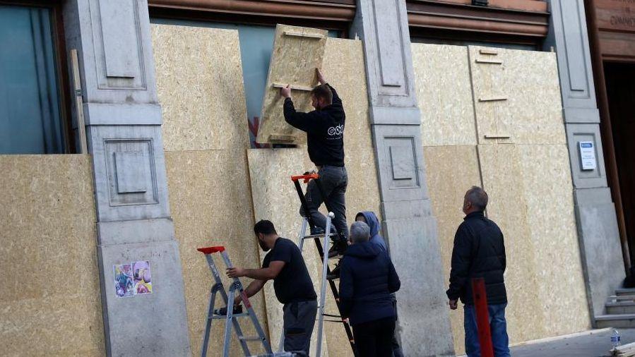 Workers boarding up windows in Lyon