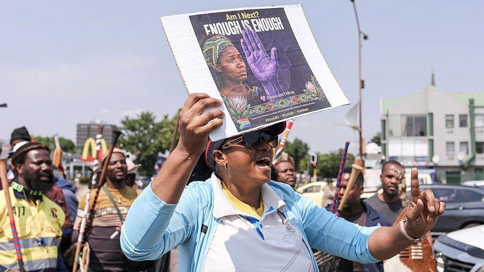 Woman holds anti‑abuse protest poster in Johannesburg