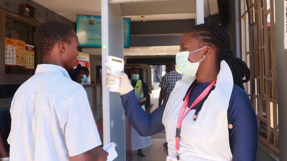 Medical staff checks a traveller’s temperature at a Kenyan border crossing