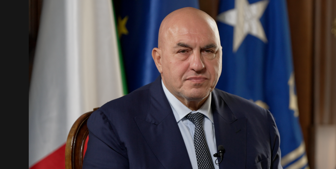 Guido Crosetto in front of Italian and EU flags