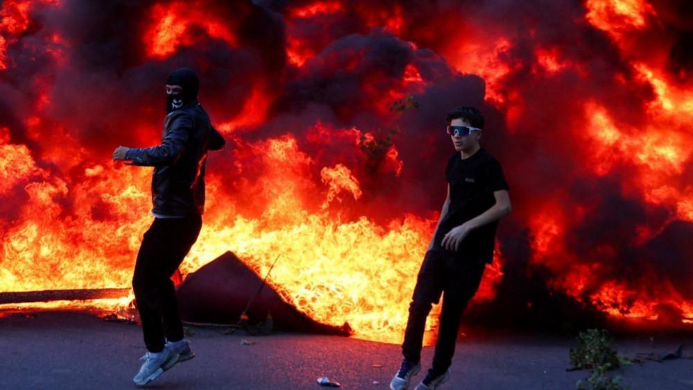 Protesters next to a smoke plume in central Tirana